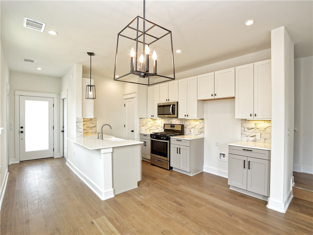 a kitchen with a sink cabinets stainless steel appliances and wooden floor