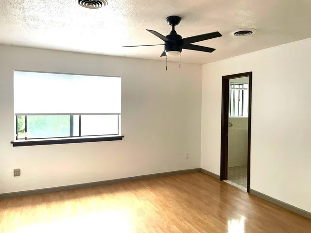 an empty room with a window and a ceiling fan