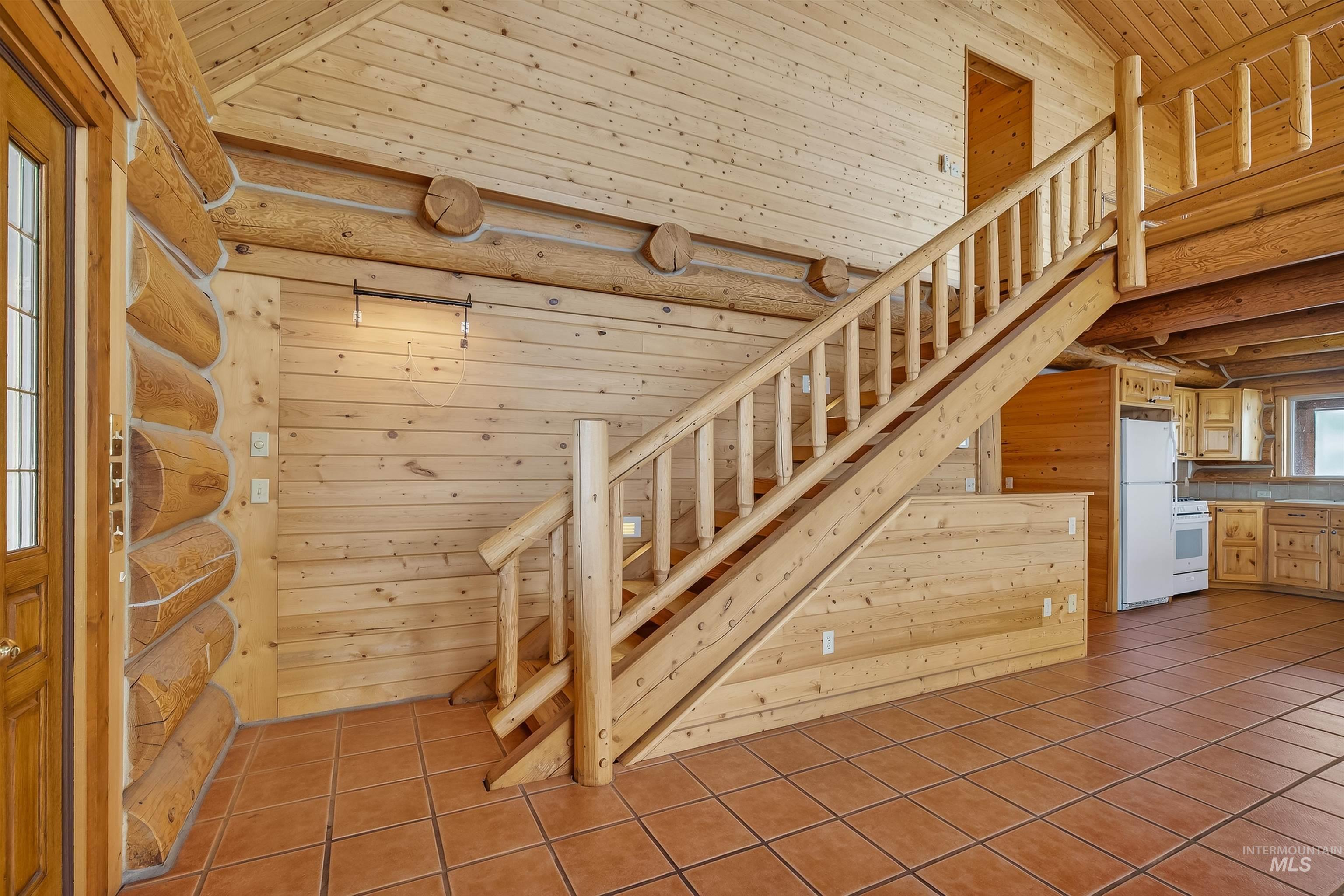 915 Doumecq Road White Bird, ID 83554 - Photo 15 of 49 Staircase with log walls, tile patterned flooring, and a high wood ceiling
