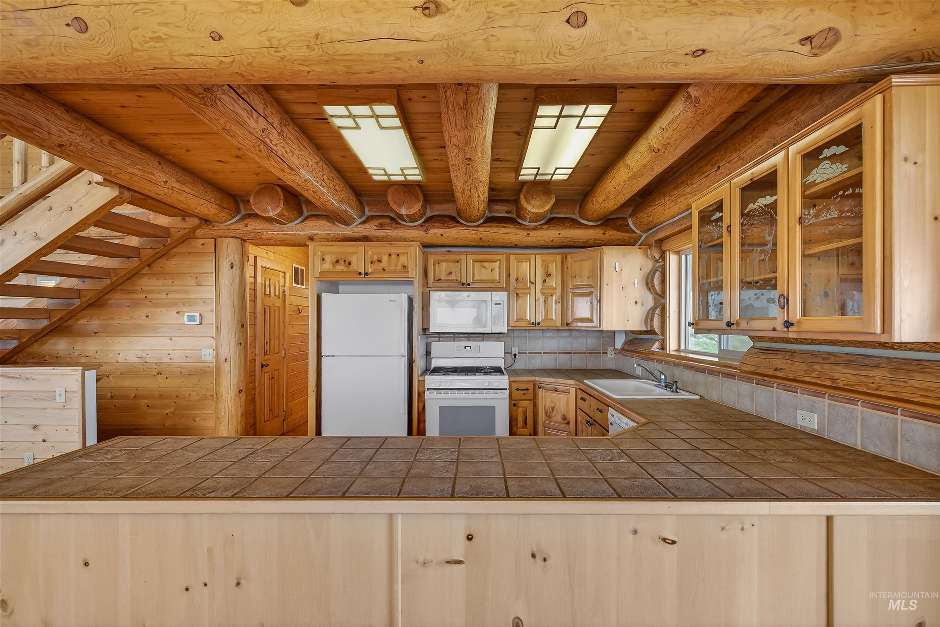 915 Doumecq Road White Bird, ID 83554 - Photo 18 of 49 Kitchen with tile countertops, white appliances, glass fronted cabinets, wood ceiling, and wood walls