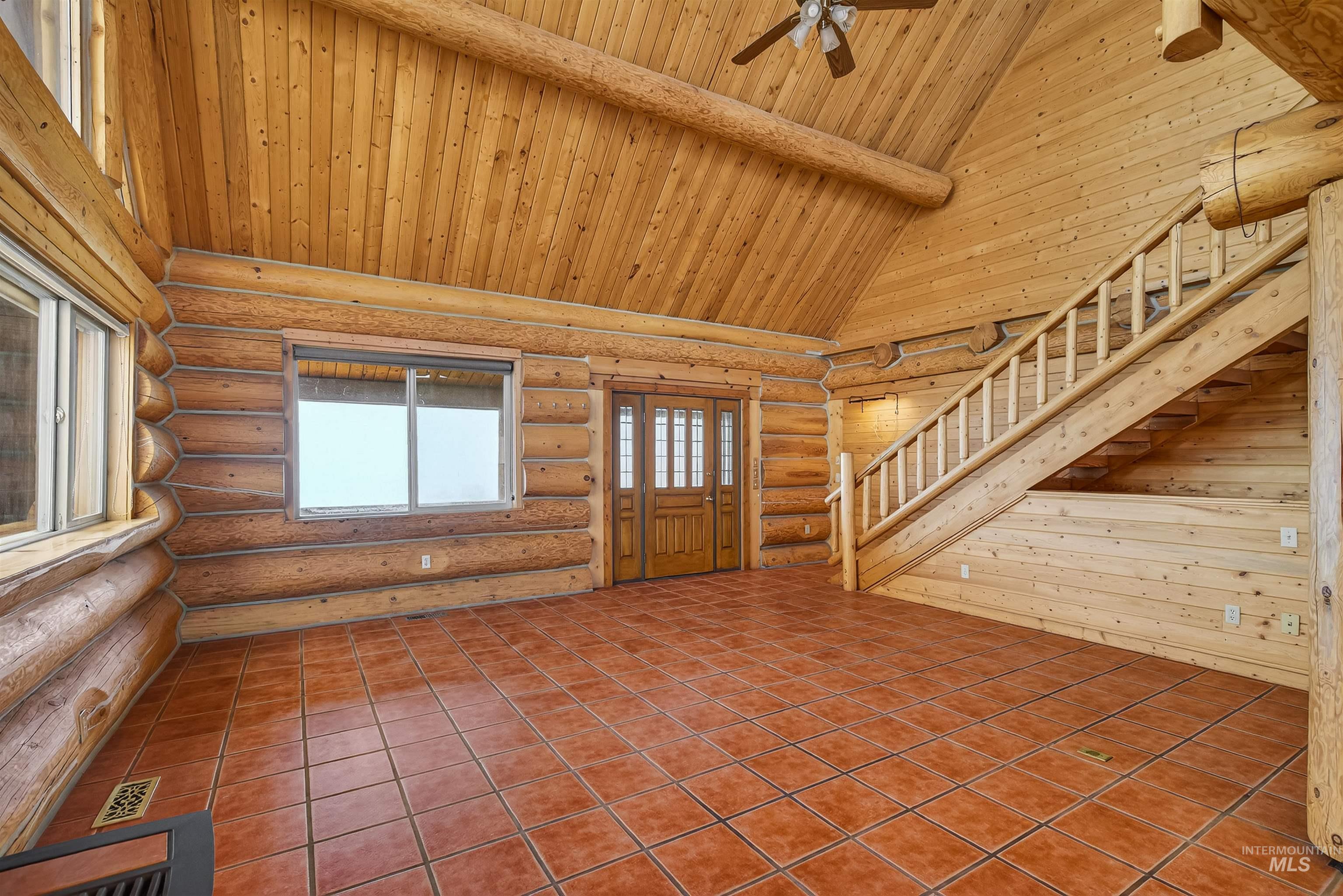 915 Doumecq Road White Bird, ID 83554 - Photo 21 of 49 Tiled foyer entrance with rustic walls, a high wooden beamed ceiling, and a ceiling fan