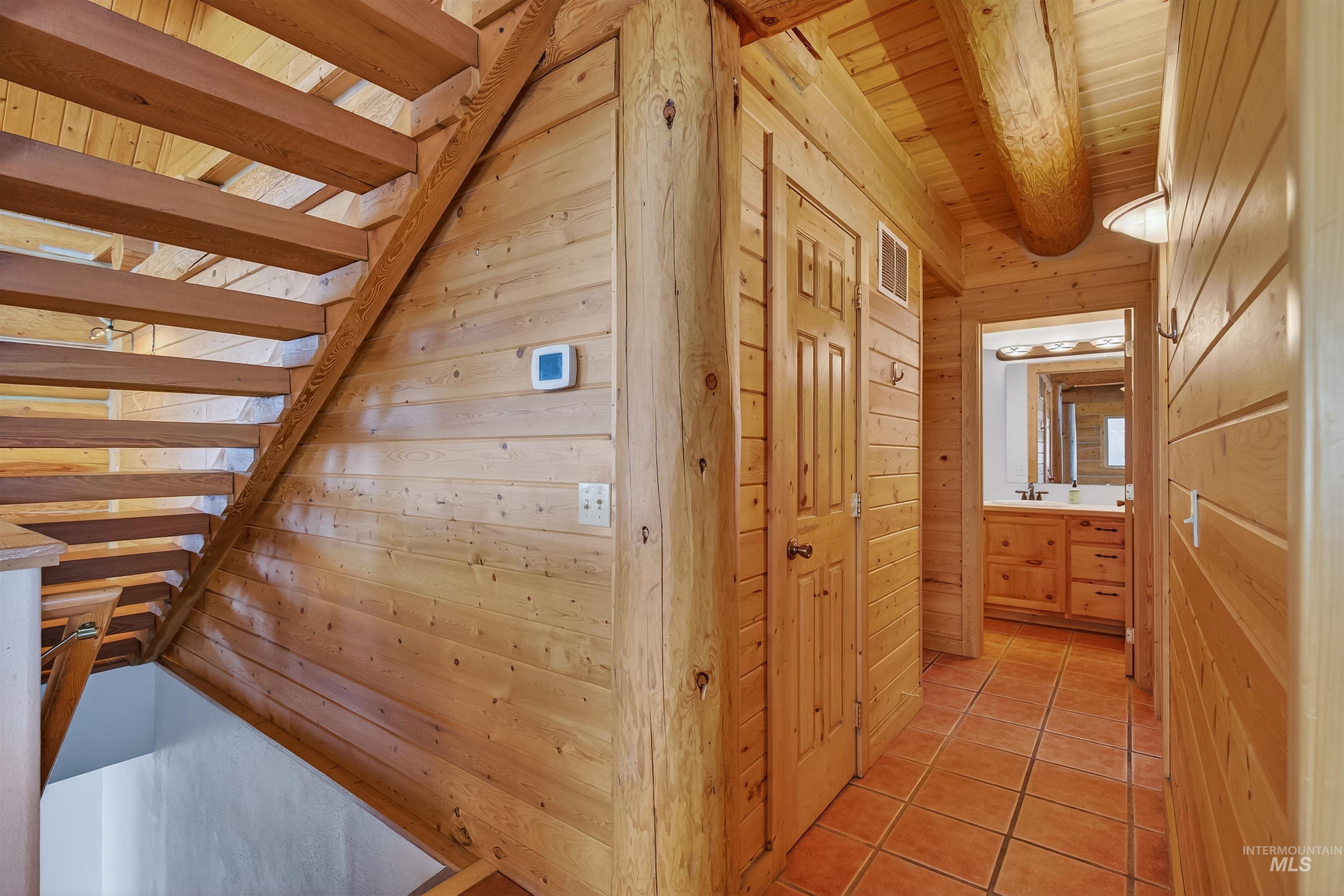 915 Doumecq Road White Bird, ID 83554 - Photo 22 of 49 Corridor with wood walls, light tile patterned floors, and a wood ceiling with exposed beams