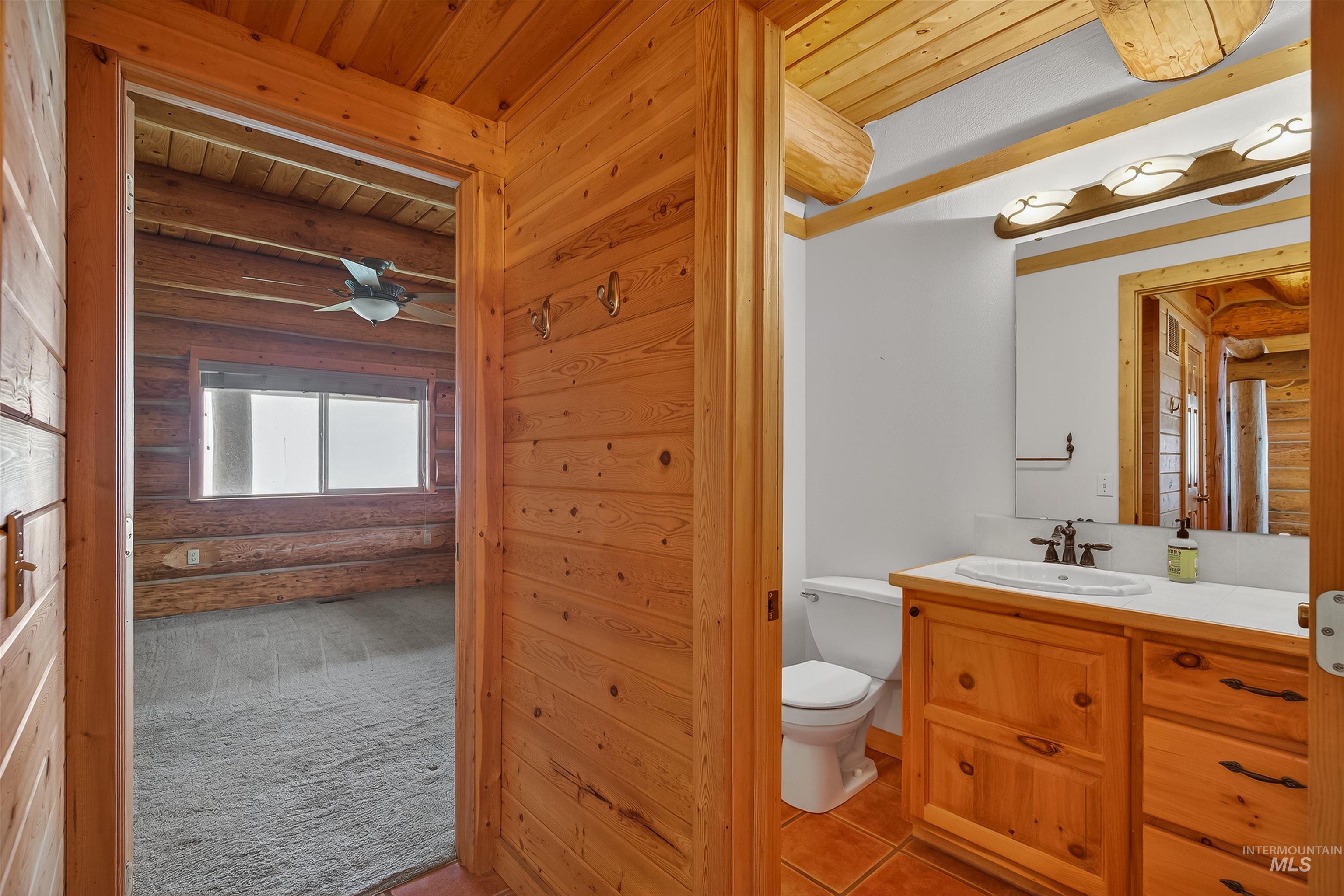 915 Doumecq Road White Bird, ID 83554 - Photo 25 of 49 Bathroom featuring a wood ceiling with exposed beams, log walls, vanity, light carpet, and light tile patterned flooring
