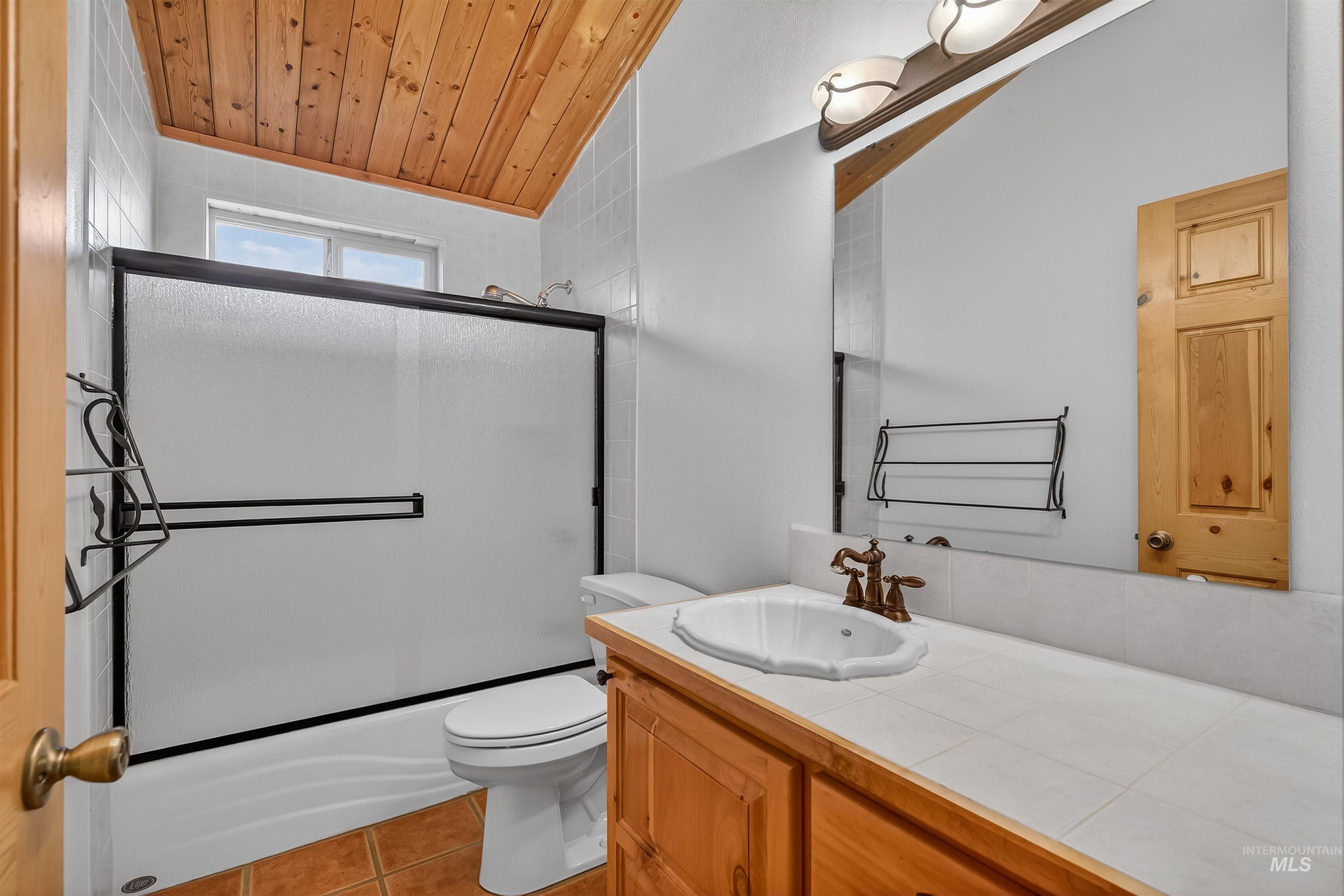 915 Doumecq Road White Bird, ID 83554 - Photo 35 of 49 Bathroom featuring vanity, a vaulted wood ceiling, bath / shower combo with glass door, and light tile patterned floors