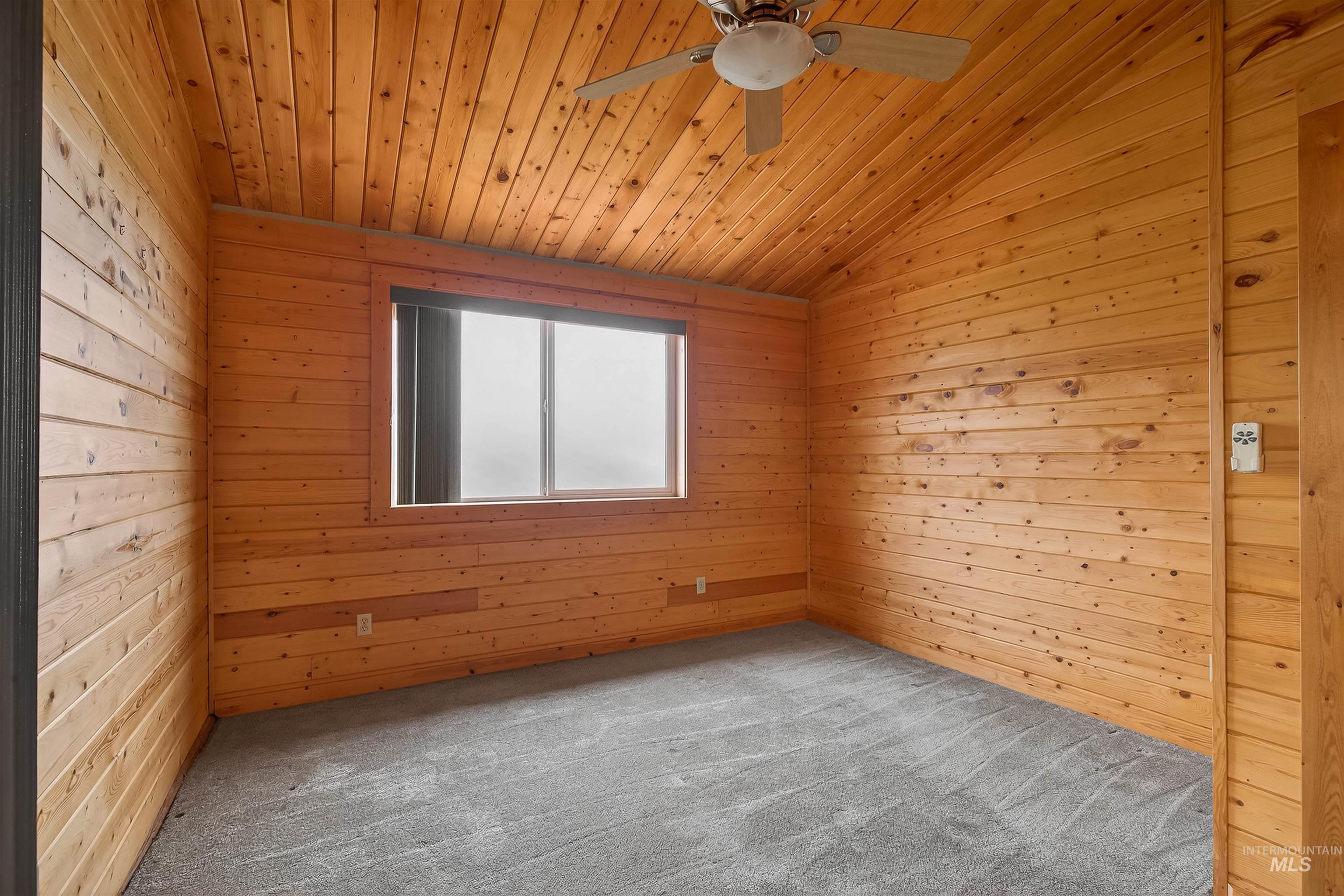 915 Doumecq Road White Bird, ID 83554 - Photo 37 of 49 Carpeted empty room featuring wood walls, ceiling fan, and a vaulted wooden ceiling