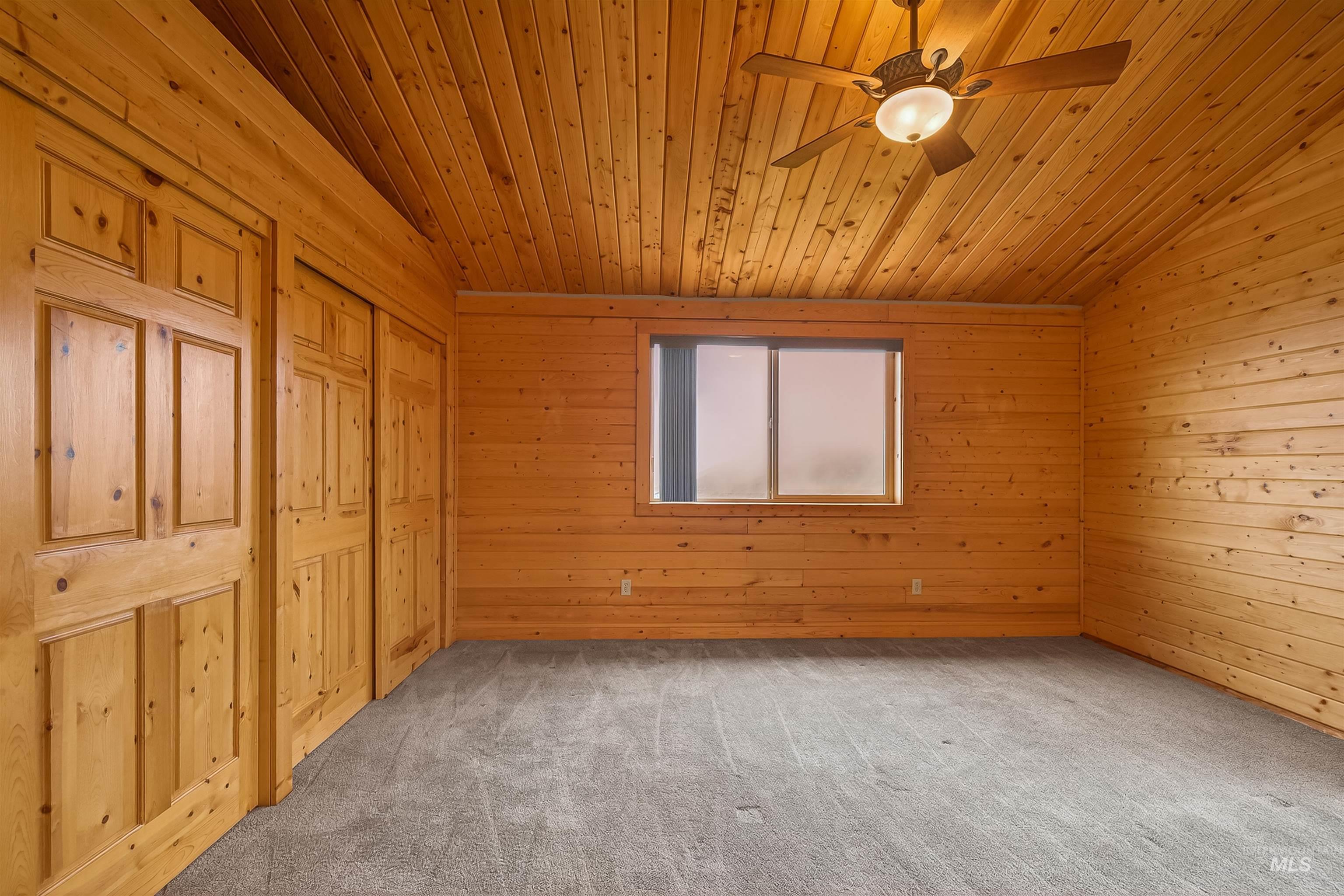 915 Doumecq Road White Bird, ID 83554 - Photo 38 of 49 Unfurnished bedroom with a closet, carpet, a ceiling fan, wooden ceiling, and wooden walls