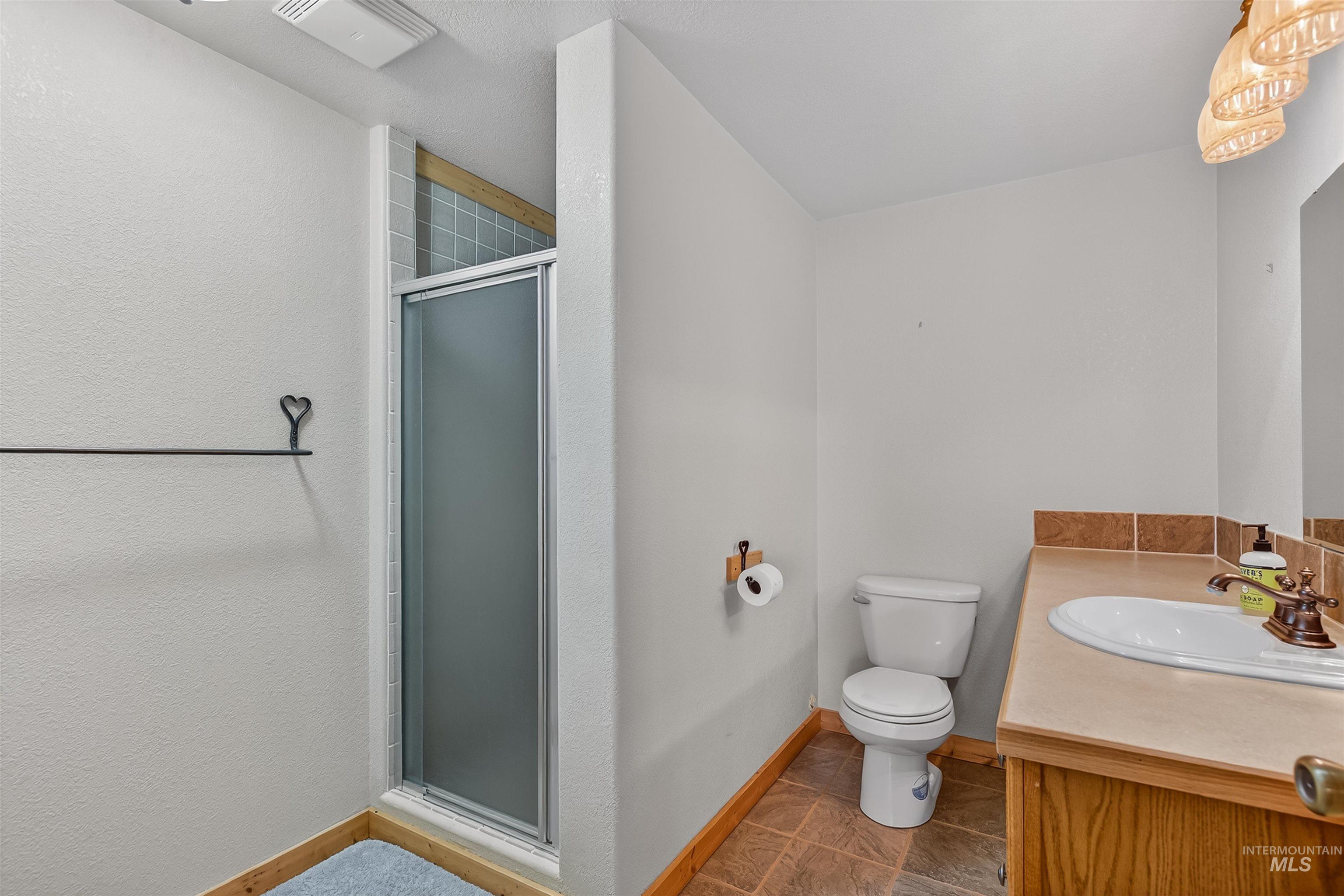 915 Doumecq Road White Bird, ID 83554 - Photo 43 of 49 Bathroom featuring a stall shower, vanity, and dark tile patterned floors