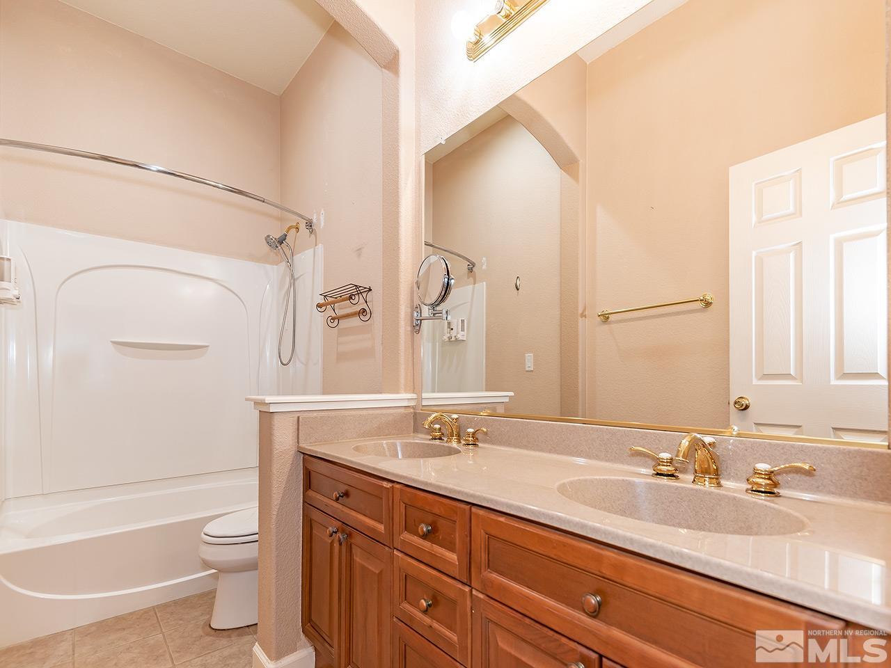 1790 Oxcart Court Reno, NV 89521 - Photo 18 of 20 a bathroom with a granite countertop sink toilet a large mirror a bathtub and shower