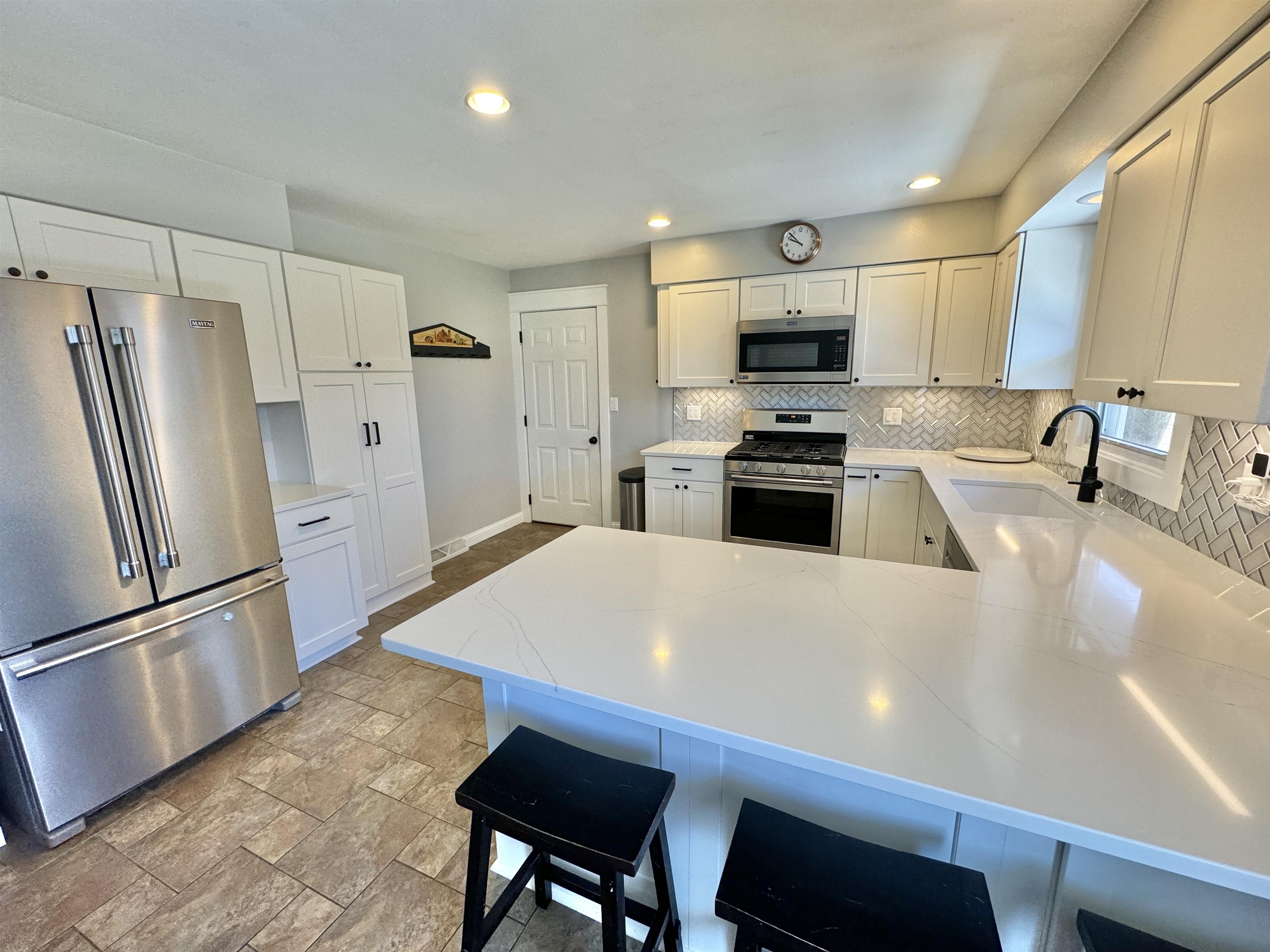 6694 Belvidere Road Roscoe, IL 61073 - Photo 14 of 32 a large kitchen with stainless steel appliances a stove a sink a refrigerator white cabinets and wooden floor