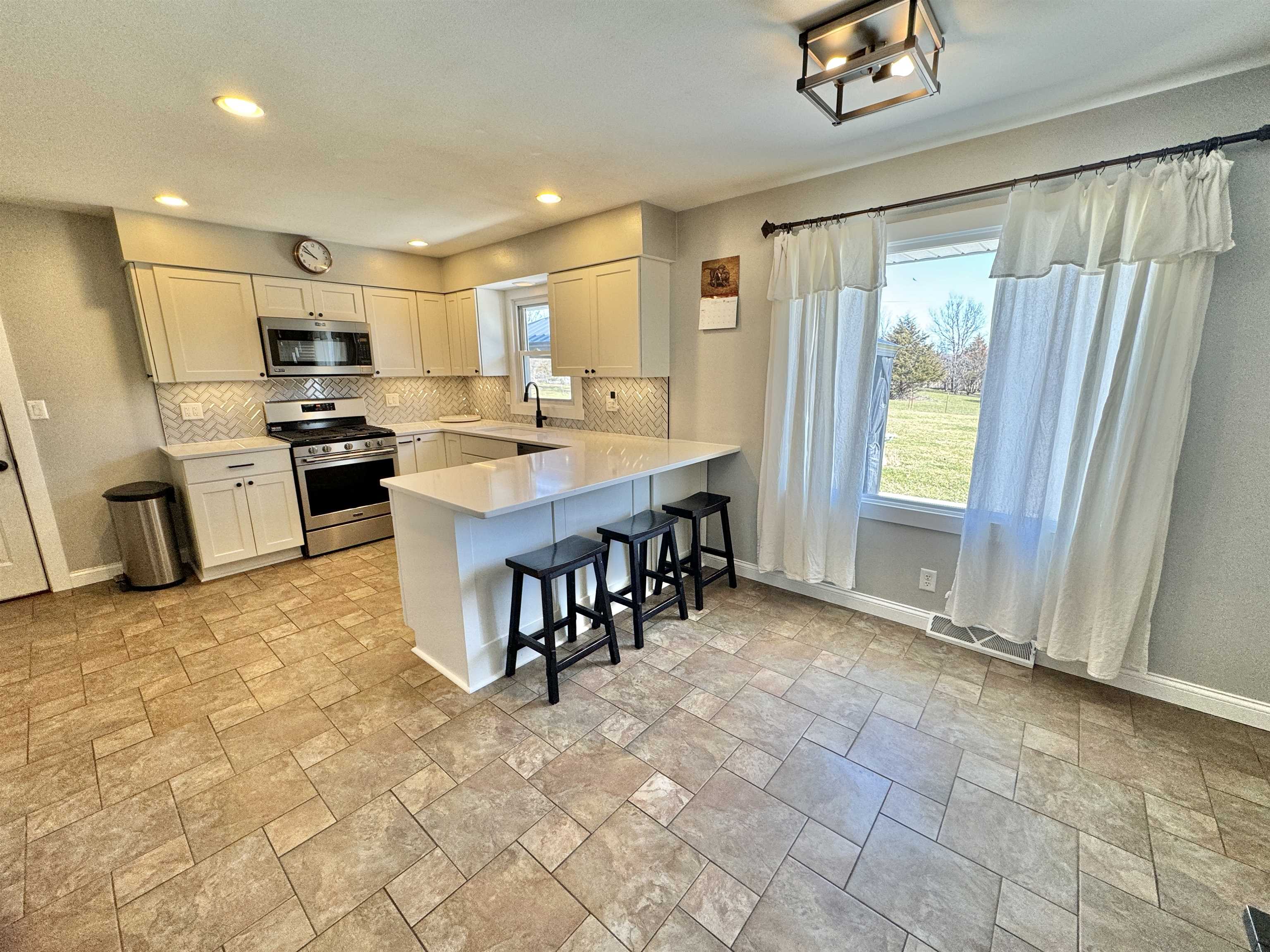 6694 Belvidere Road Roscoe, IL 61073 - Photo 17 of 32 a large kitchen with kitchen island granite countertop a large counter top space appliances and cabinets