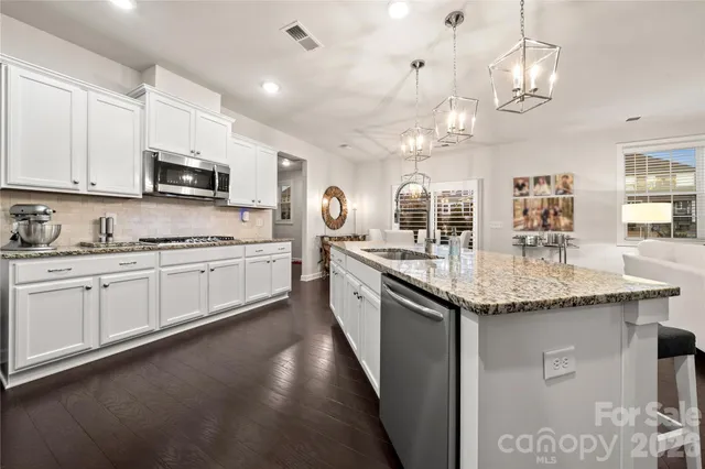 a kitchen with stainless steel appliances granite countertop a sink a stove and cabinets