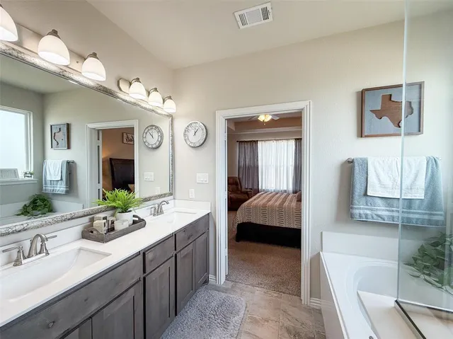 a spacious bathroom with a bathtub shower sink double vanity and mirror