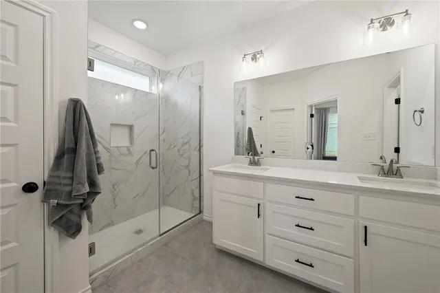 a bathroom with a double vanity sink a mirror and a shower
