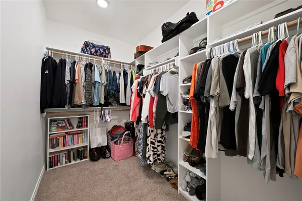 a view of walk in closet with clothes and shoes