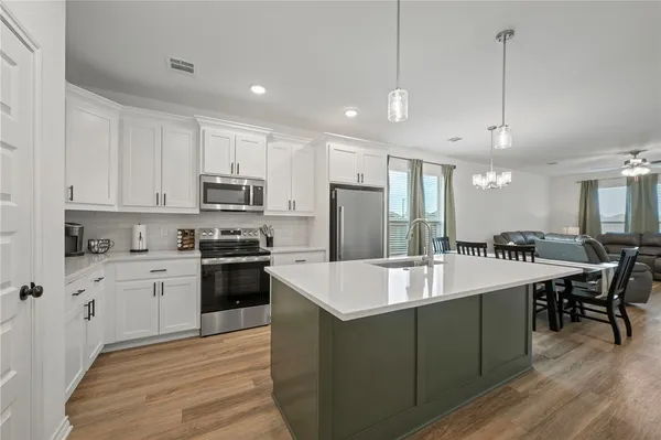 a large kitchen with kitchen island a island a stove a sink a center island and a refrigerator