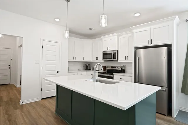 a kitchen with kitchen island white cabinets and stainless steel appliances