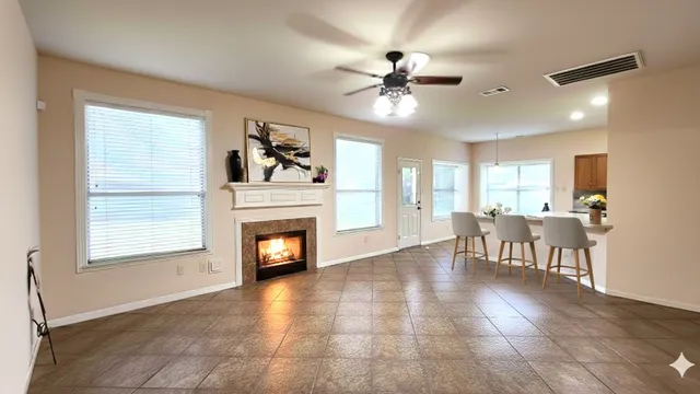 a view of a livingroom with a fireplace a ceiling fan and windows