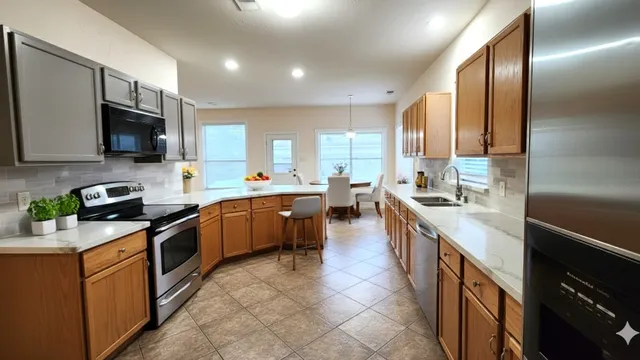 a kitchen with stainless steel appliances granite countertop a stove top oven a sink dishwasher a refrigerator and a microwave