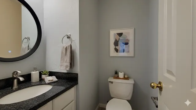 a bathroom with a granite countertop sink mirror and toilet