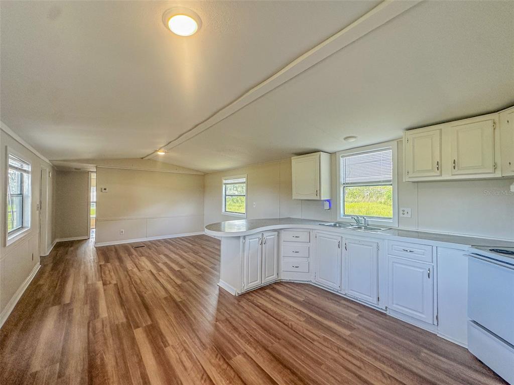 2218 Ellie Road, Unit 1 Auburndale, FL 33823 - Photo 3 of 21 a kitchen with wooden floors and white cabinets