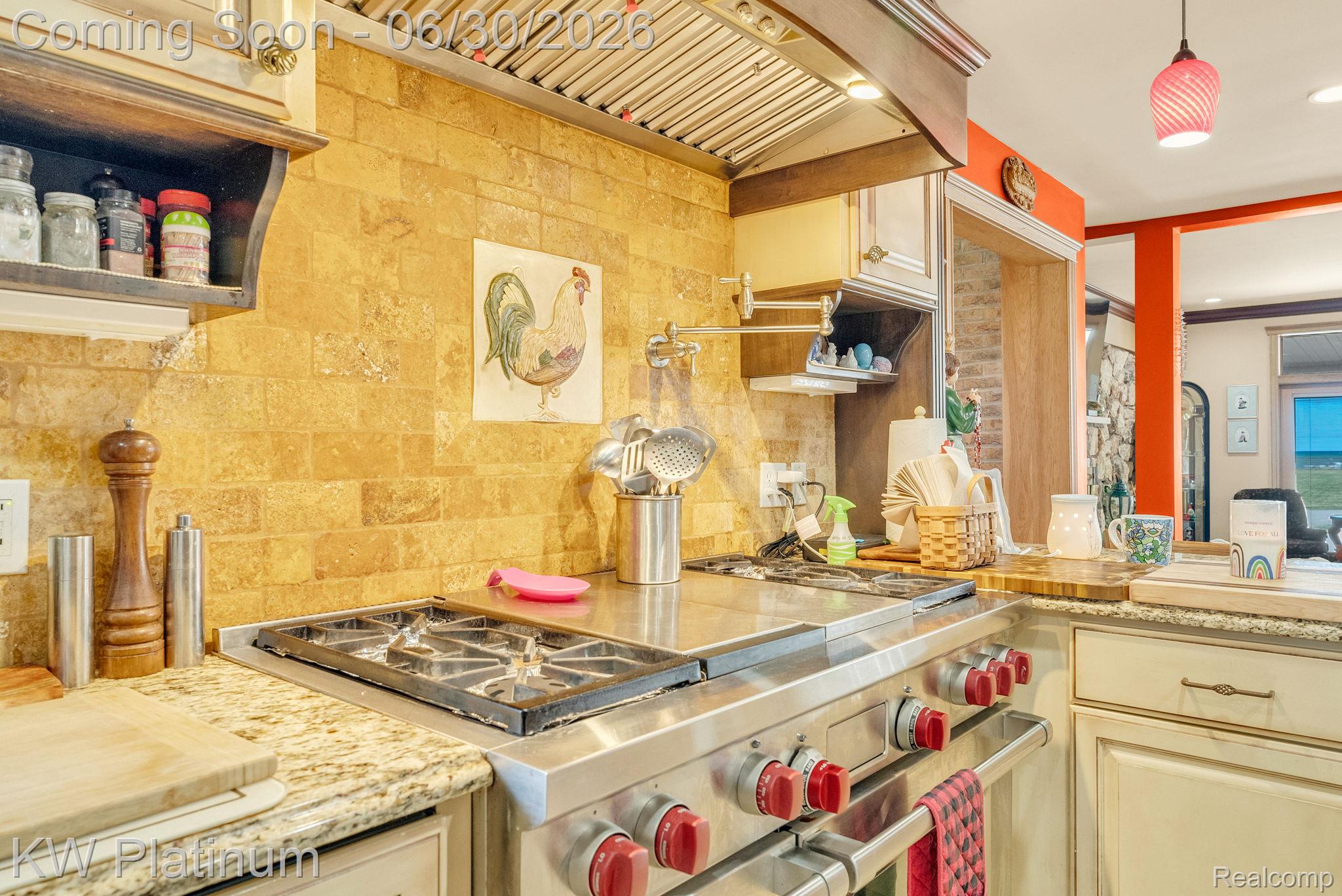2235 South Lake Shore Road Harbor Beach, MI 48441 - Photo 12 of 99 Professional-grade stainless steel range with red accent knobs, complemented by a stone tile backsplash and granite countertops