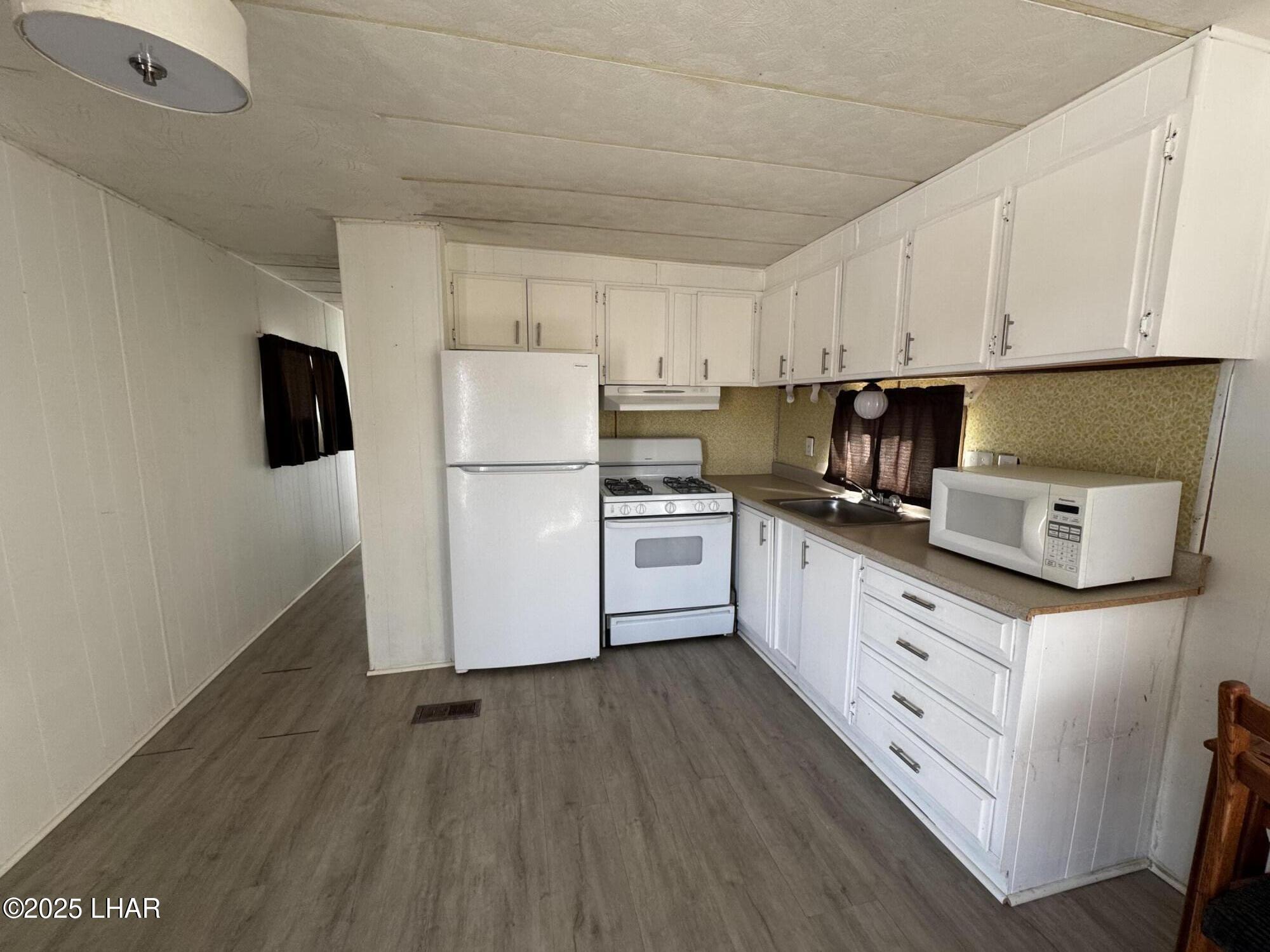 10186 Harbor View Road Parker, AZ 85344 - Photo 5 of 16 a kitchen with cabinets stainless steel appliances a sink and wooden floor