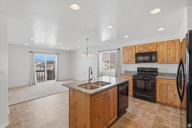1218 Moonlight Drive Elk Ridge, UT 84651 - Photo 9 of 44 Kitchen featuring black appliances, light stone counters, a textured ceiling, stone finish floors, and a center island with sink