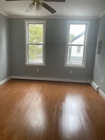 an empty room with wooden floor and windows