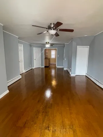 a view of an empty room with window and chandelier fan