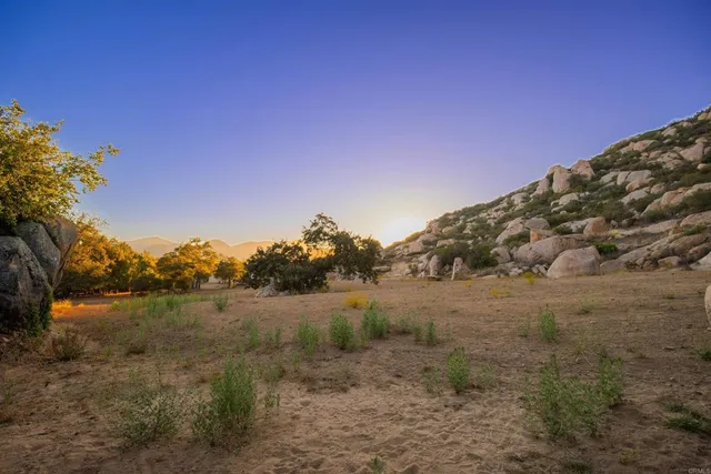 a view of a dry field with mountains in the background