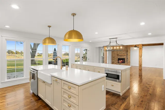 a kitchen with stainless steel appliances granite countertop a sink a stove and a wooden floors