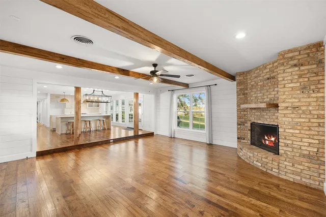 a view of an empty room with wooden floor fireplace and a window