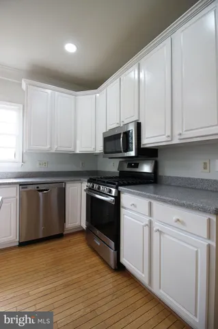 a kitchen with granite countertop white cabinets and appliances