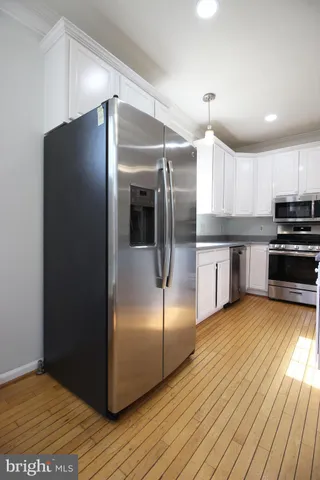 a kitchen with kitchen island a counter top space wooden floor and stainless steel appliances
