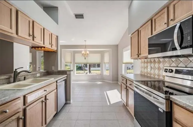 a kitchen with granite countertop a sink stainless steel appliances and white cabinets