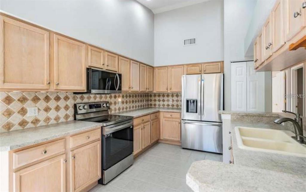 1520 Canberley Court Trinity, FL 34655 - Photo 12 of 35 a kitchen with granite countertop a sink stainless steel appliances and white cabinets