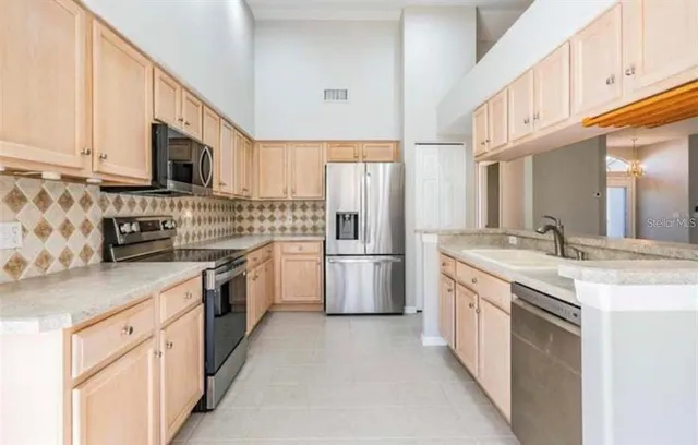 a kitchen with stainless steel appliances granite countertop a refrigerator a stove a sink and a microwave