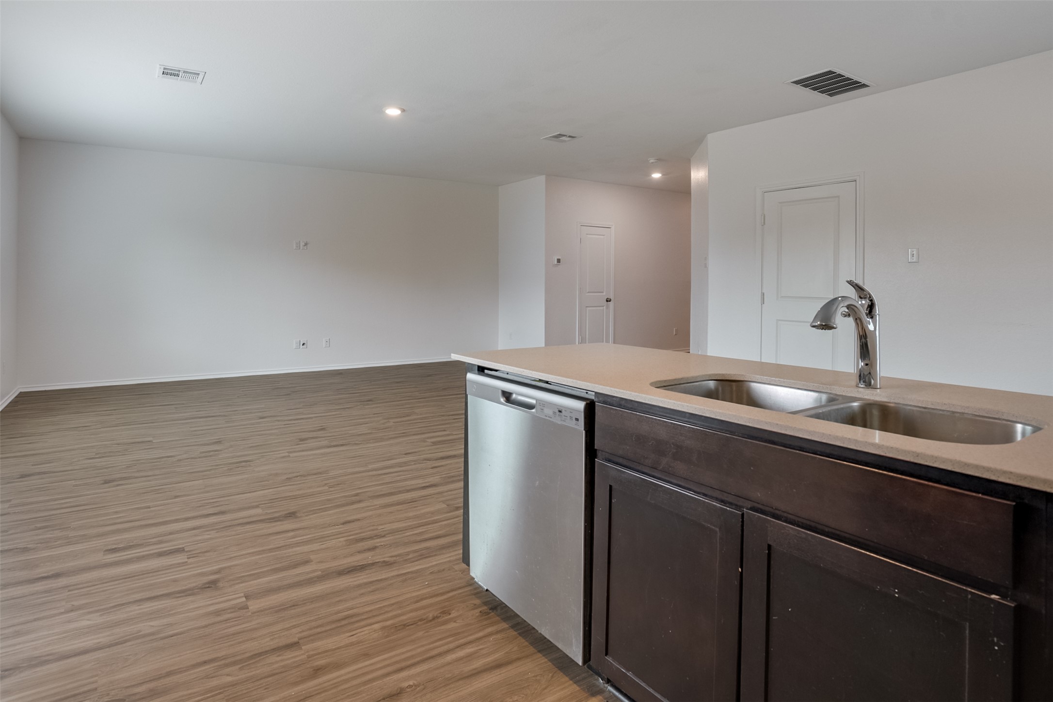 428 Gabbro Gardens Maxwell, TX 78656 - Photo 23 of 26 Kitchen with dark wood finish cabinetry, stainless steel dishwasher, light stone countertops, dark wood-style flooring, and open floor plan