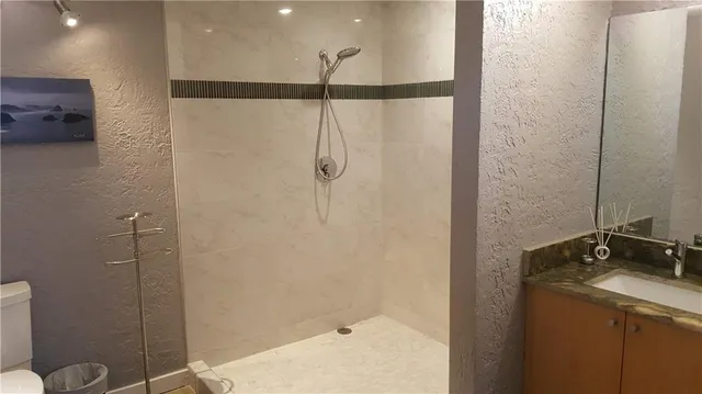 a bathroom with a granite countertop sink a toilet and shower