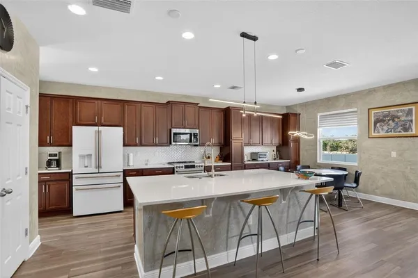 a kitchen that has a sink a microwave oven a stove and white cabinets with wooden floor