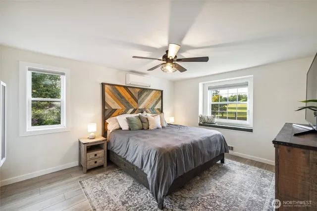 a bedroom with a large bed a flat tv screen and a dresser