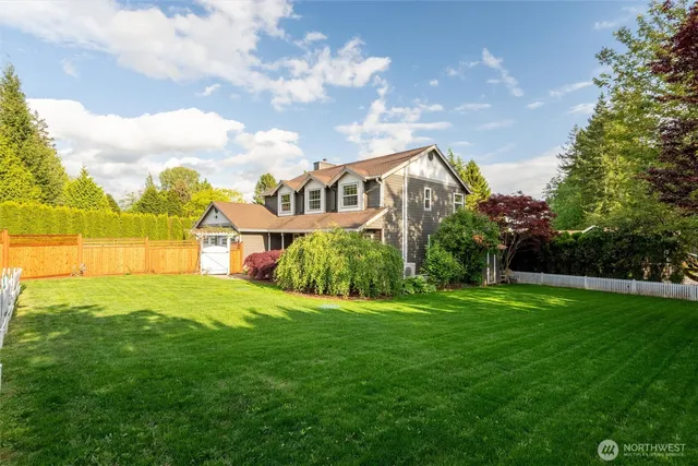 a view of a house with a big yard and a large trees