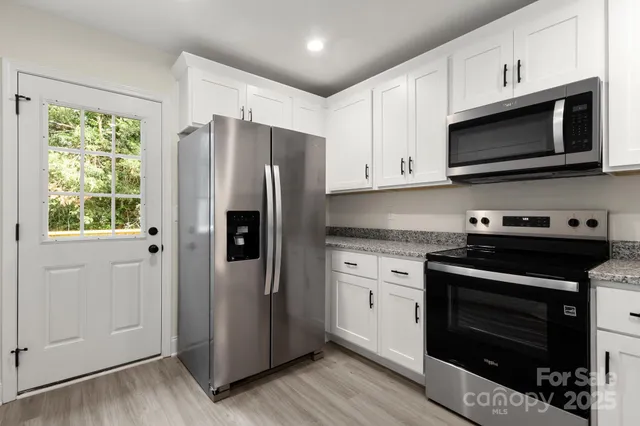a kitchen with stainless steel appliances white cabinets a stove a microwave and a refrigerator