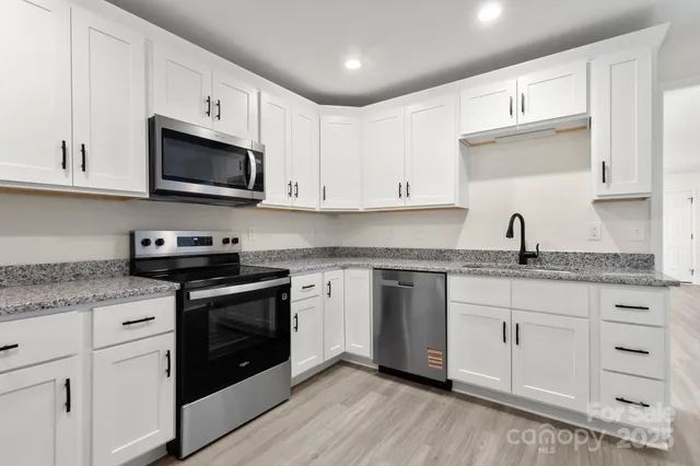 a kitchen with granite countertop white cabinets white stainless steel appliances and a sink