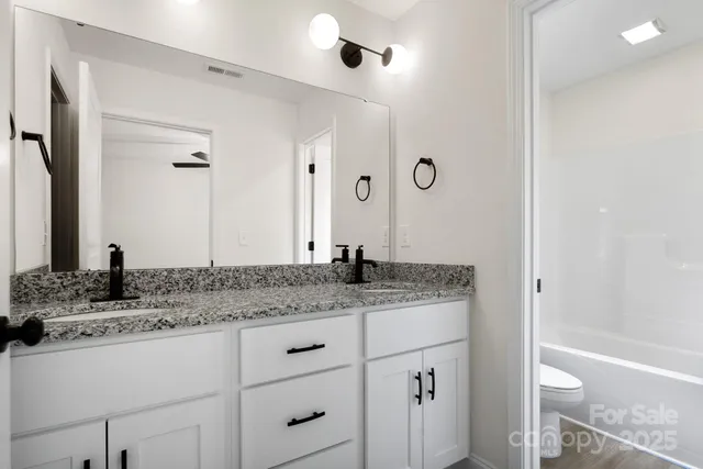 a bathroom with a granite countertop sink a mirror and a bathtub