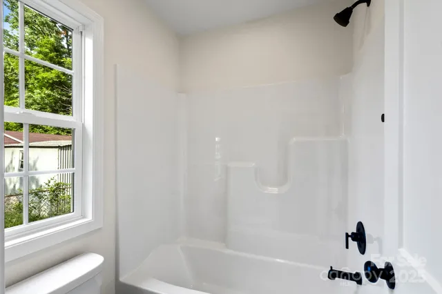 a bathroom with a bathtub a window and a shower