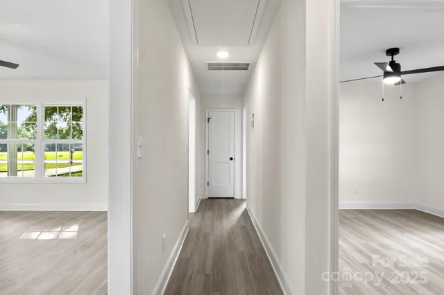 a view of a hallway with wooden floor and a bathroom