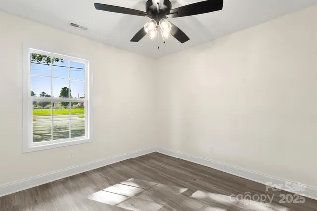 a view of empty room with wooden floor and ceiling fan
