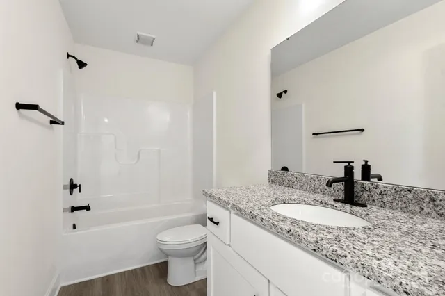 a bathroom with a granite countertop sink a toilet and shower