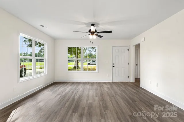 a view of an empty room with a window and wooden floor
